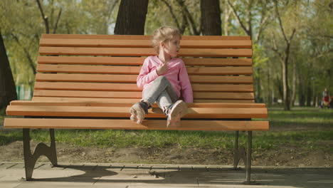 little girl suffers from hot weather sitting on park bench