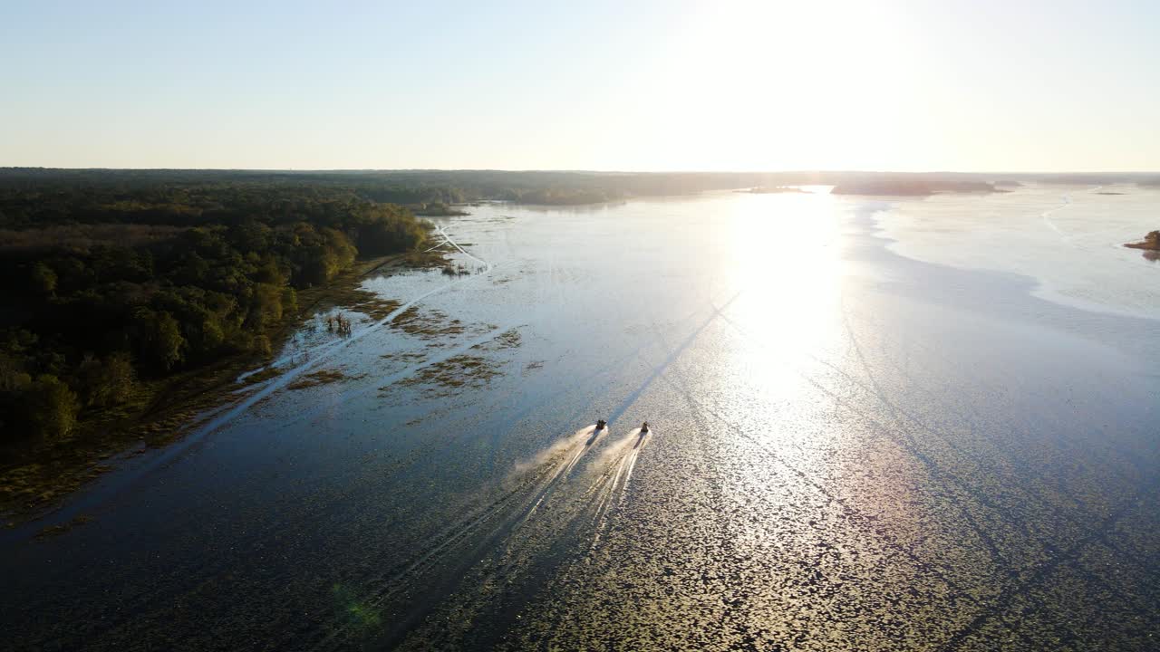 воздушные лодки, скользящие по озеру во флориде при заходе солнца, создавая тропы на поверхности воды, воздушный клип