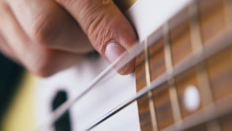 el dedo del bajista toca la cuerda de acero inoxidable de la guitarra