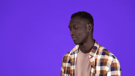 A-short-haired-young-african-american-man-is-yawning,-touching-his-face,-tired-and-sleepy-standing-isolated-over-blue-wall-background-in-studio.-Side-view