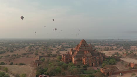 Buddhist-temple-in-hazy-landscape-of-Myanmar-with-traditional-hot-air-balloons