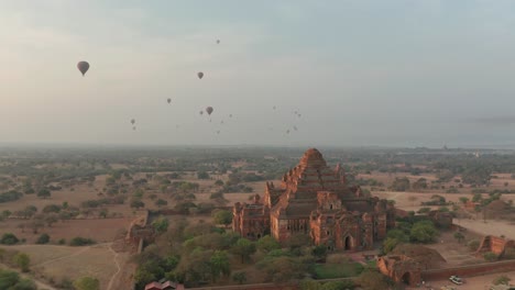 templo budista en el brumoso paisaje de myanmar con globos aerostáticos tradicionales