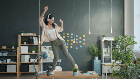 woman dancing on desk with headphones
