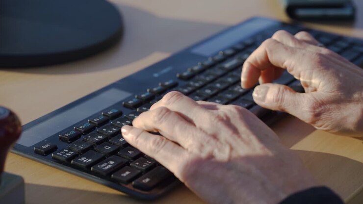 Primo piano delle mani di un uomo che digita su una tastiera di computer.