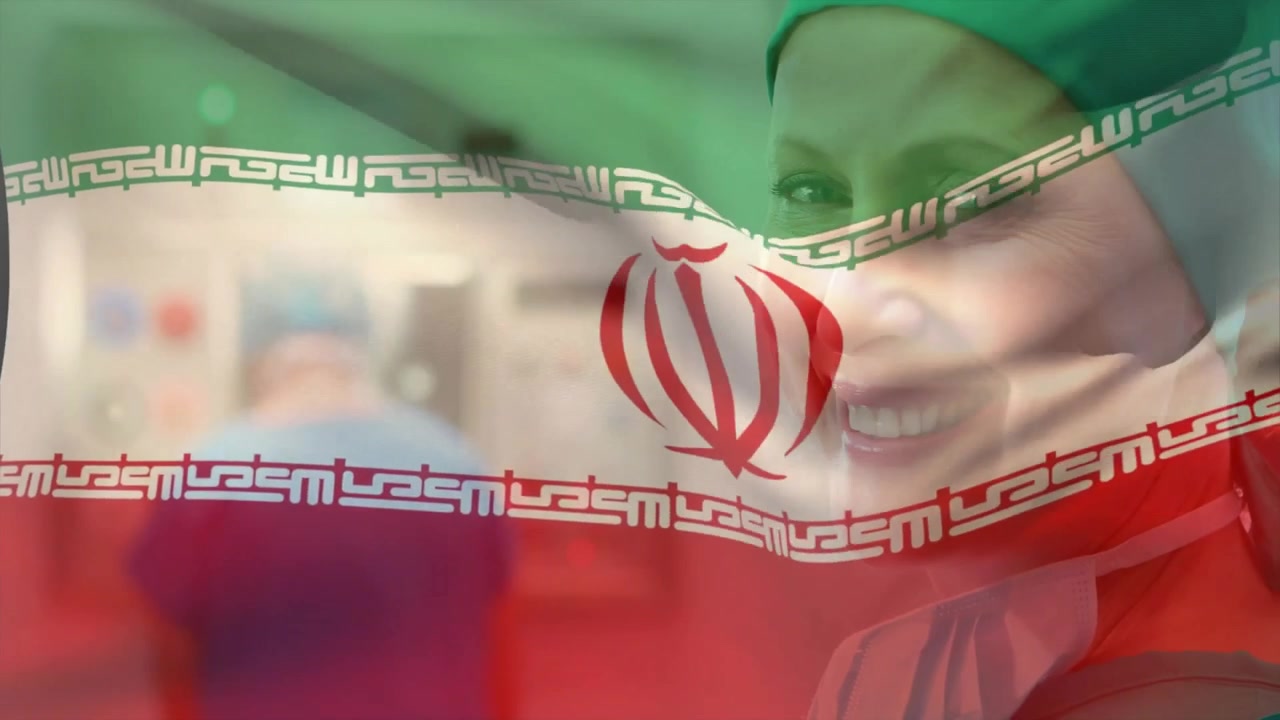 Tangan bersarung tangan mengangkat bendera Iran, memperlihatkan ahli bedah wanita tersenyum dengan masker diturunkan di ruang operasi rumah sakit.