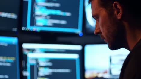 a focused programmer analyzing multiple screens of code and data in a dimly lit environment, showcasing the deep concentration in software development