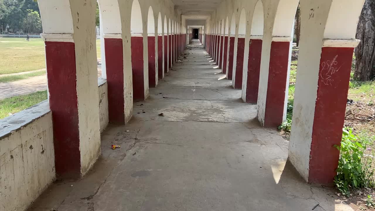 Old vacant corridor painted with series of arched openings on both sides in India.