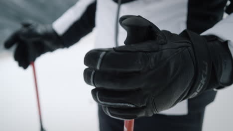 close up shot of a woman in skiing gear and gloves on her hands takes in hands skiing poles