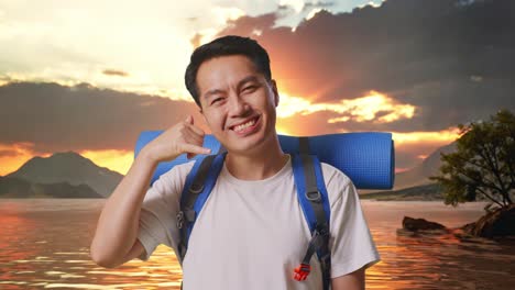 close up of asian male hiker with mountaineering backpack smiling and showing call me gesture at a lake