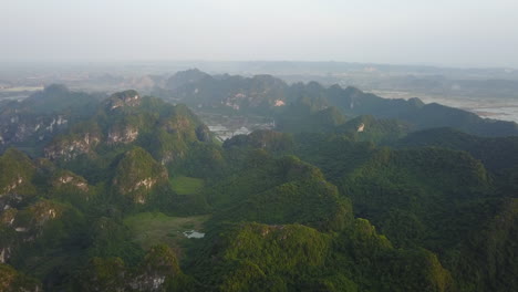 witness a breathtaking panoramic view of the iconic rock formations in ninh binh, vietnam, at dawn. the scene captures the first light of day illuminating the majestic limestone karsts.