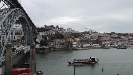 tourists on rabelo boat almost crossing under dom luis i bridge, porto