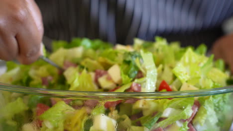 mixing together a chopped salad and dressing - antipasto salad series