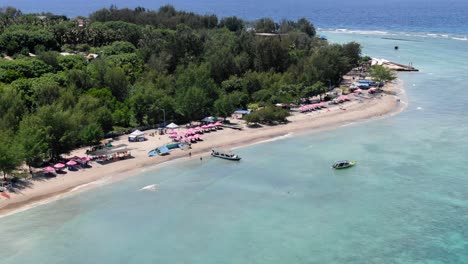 aerial view of gili trawangan beach with pink beach umbrellas and tourist roaming about