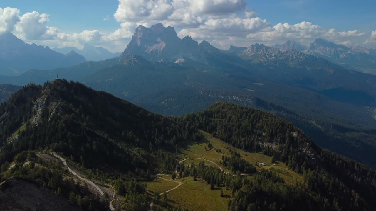 Veduta aerea su un paesaggio collinare verde e boscoso con un orizzonte blu e nuvoloso a Monte Rite, Dolomiti, Italia