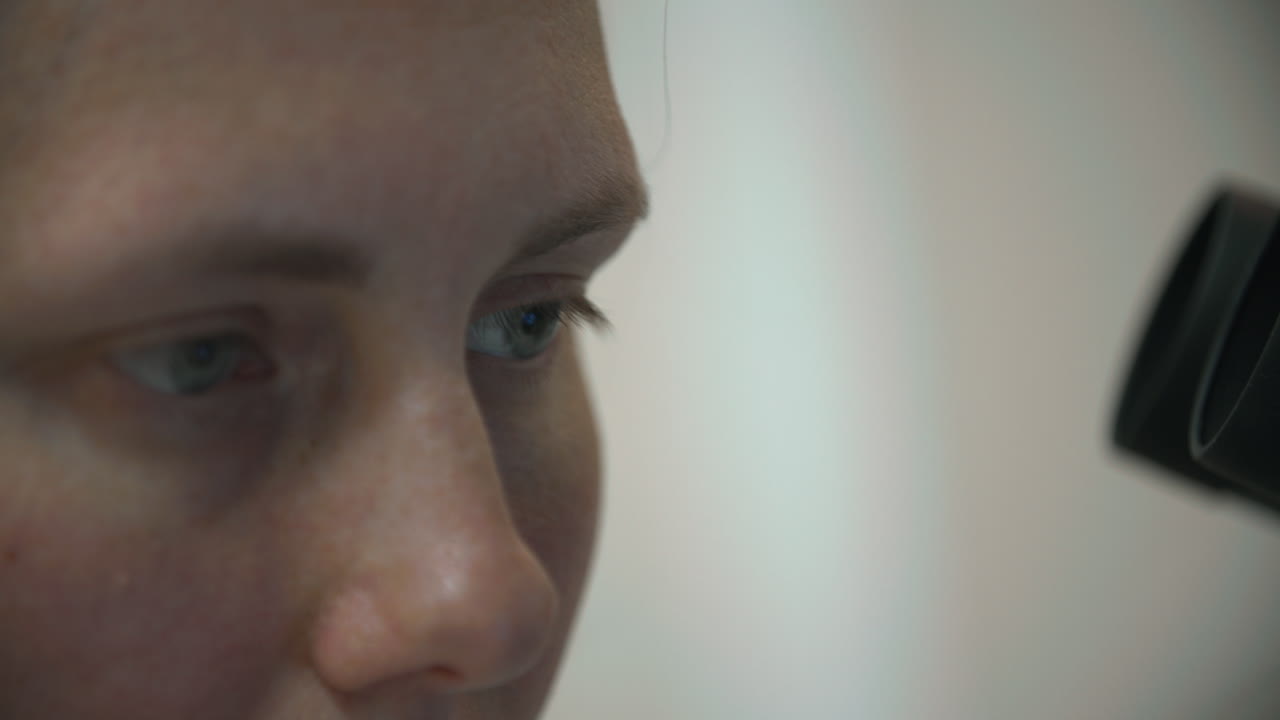Close-up of Woman's Eyes Looking Through Microscope