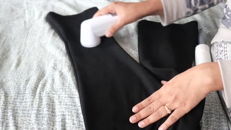 woman using a lint roller to clean black pants