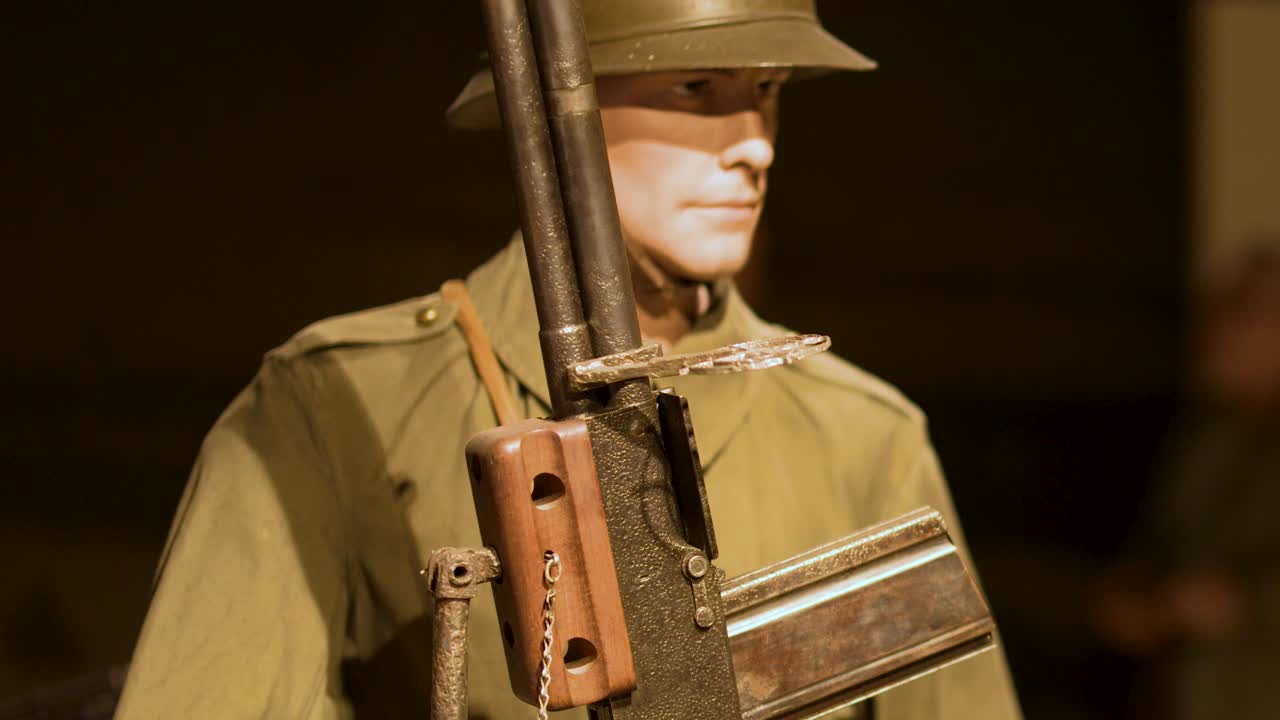 Static mannequin in World War II uniform, holding machine gun, warmly lit, museum display setting