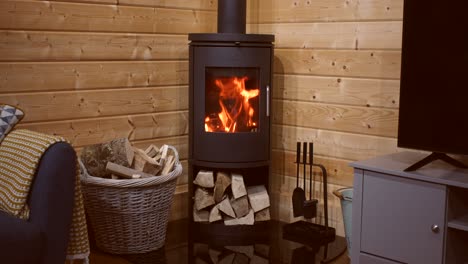wide-shot-of-a-fire-in-a-wood-burner-with-kindling-and-logs-in-a-log-cabin