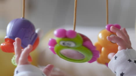 infant grabbing plastic toys overhead