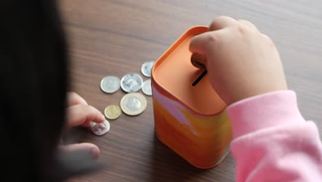 niño ahorrando dinero en una caja de cerdos de hojalata colorida