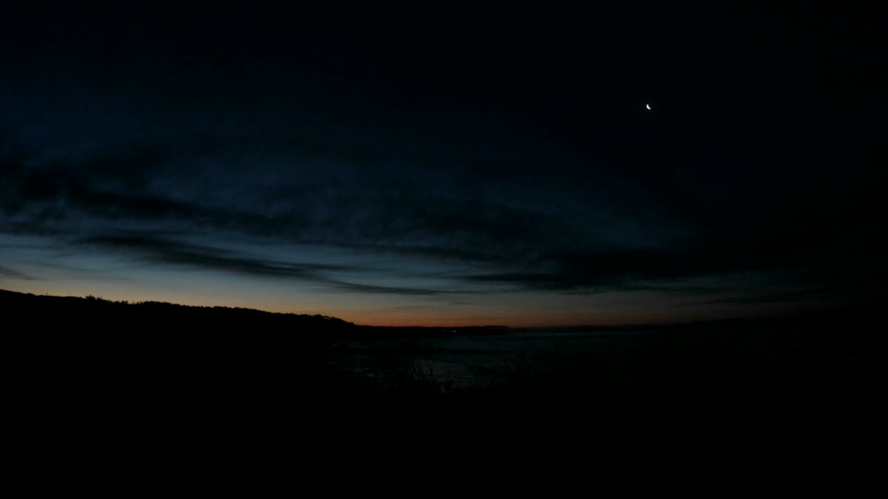 nuvens escuras movem-se rapidamente sobre uma linha costeira enquanto o céu se ilumina