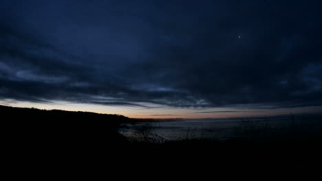 Dark-clouds-move-quickly-over-a-shoreline-as-the-sky-brightens