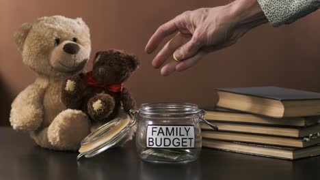 man puts coins into empty jar for family savings