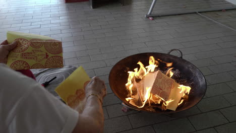 over-shoulder shot, put joss paper into the flame