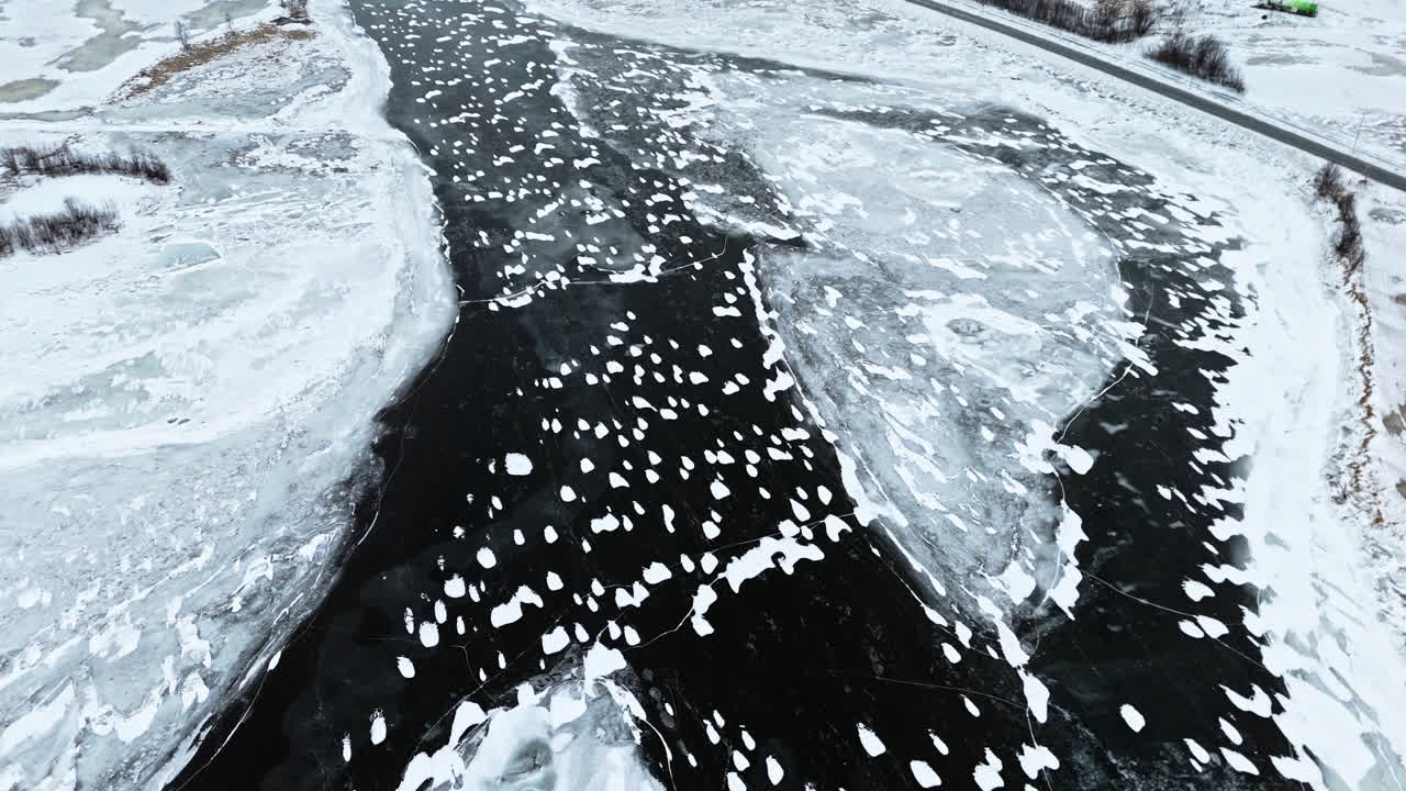 Frozen Tromsø fjords with cracked ice, dark water patches, and snowy landscape