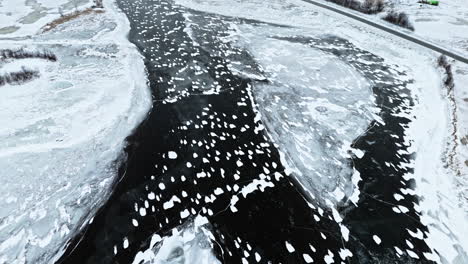 frozen tromsø fjords with cracked ice, dark water patches, and snowy landscape