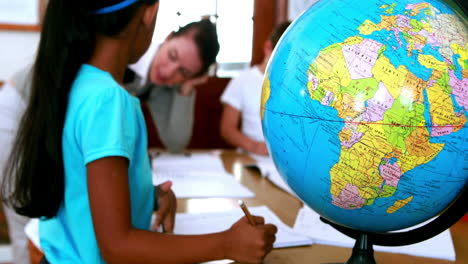 pupils all siting around table working with focus on globe