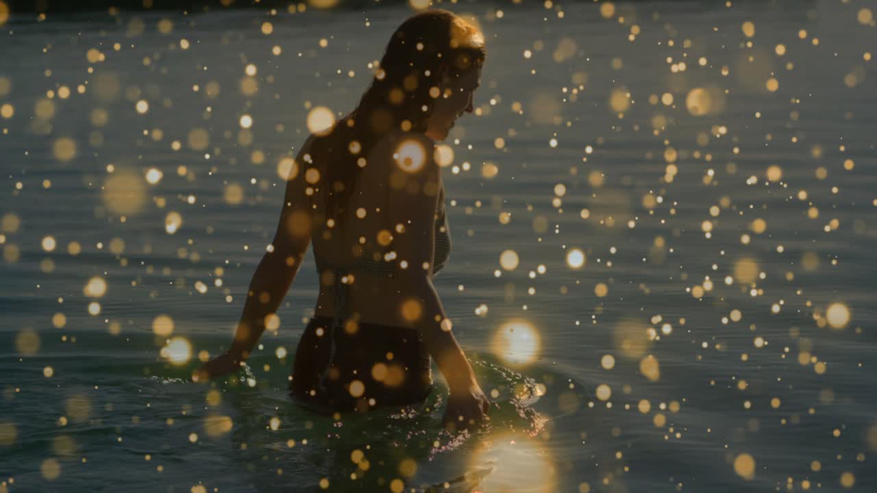 Donna che cammina nell'acqua del mare all'ora d'oro, con effetto bokeh del tramonto in sovrimpressione che accentua le increspature e il benessere.