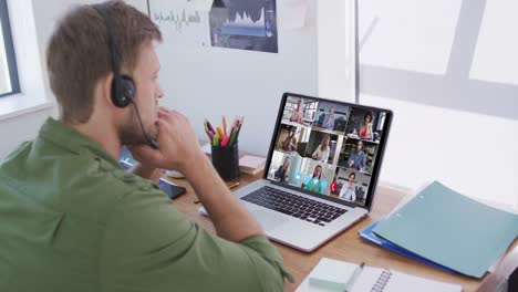 Caucasian-man-using-laptop-and-phone-headset-on-video-call-with-colleagues