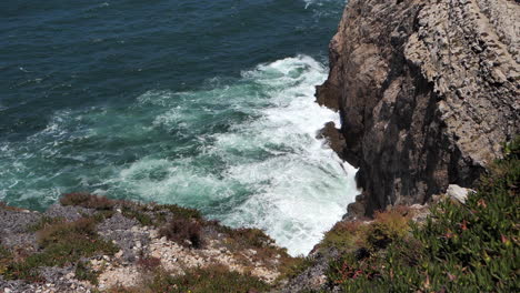 Slow-Motion-of-Ocean-Waves-Breaking-on-Steep-Rocky-Cliffs-in-Sagres,-Algarve-Portugal,-High-Angle-View