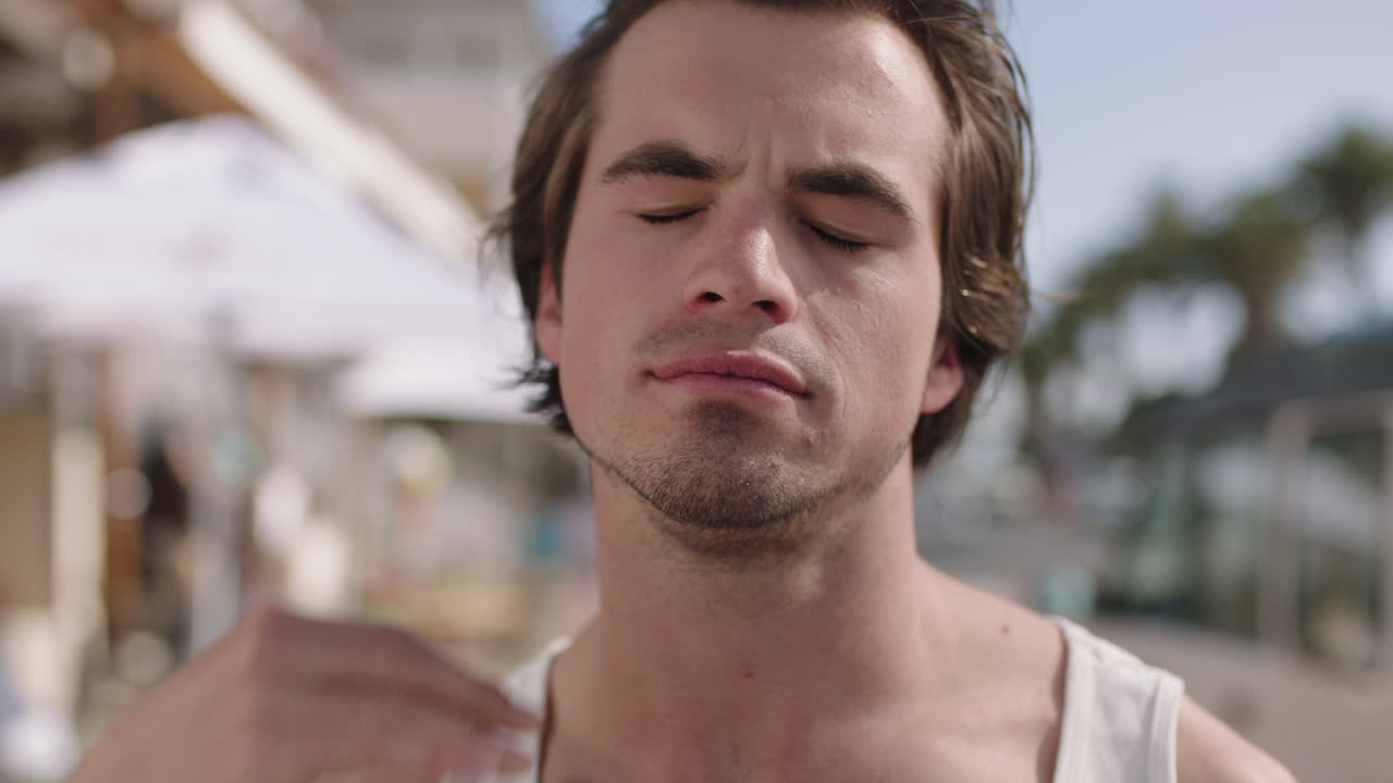 retrato de cerca de un joven atractivo corriendo con la mano a través del cabello sonriendo con confianza