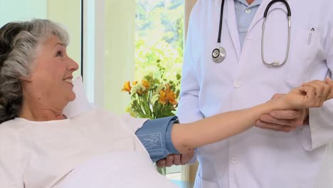 Male-doctor-measuring-blood-pressure-at-his-female-patient