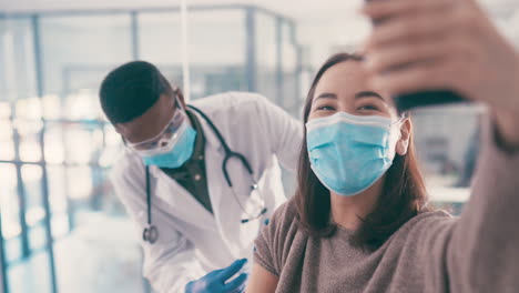 woman getting vaccinated and taking a selfie with doctor