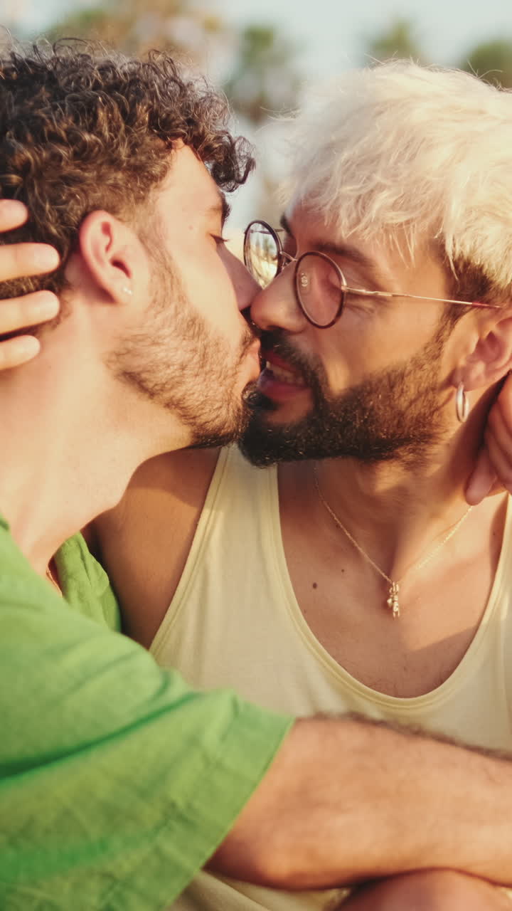 Primo piano di una coppia gay felice che si bacia all'aperto sotto la luce del sole