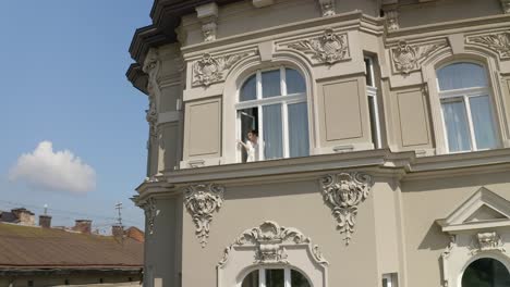 Aerial-shot-of-bride-in-boudoir-dress-stay-near-window-wedding-morning-of-woman-in-night-gown,-veil