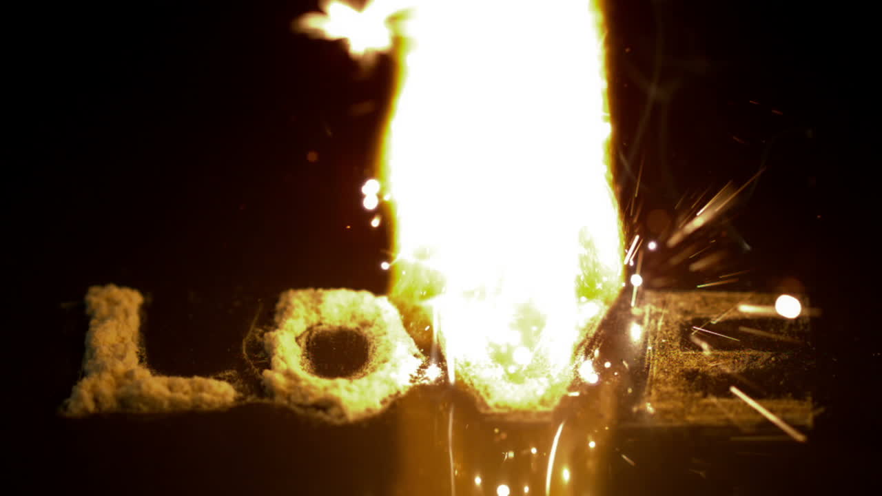 불은 검은 표면에 사랑이라는 단어를 태우고 있습니다.