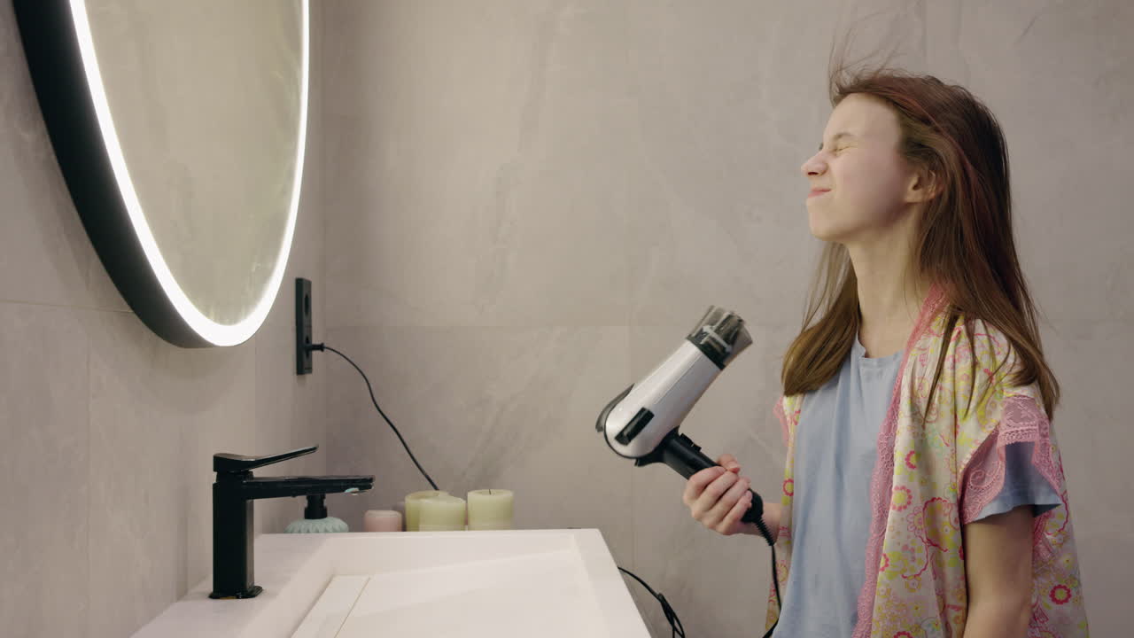 Teenage girl drying her hair in the bathroom