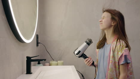 teenage girl drying her hair in the bathroom