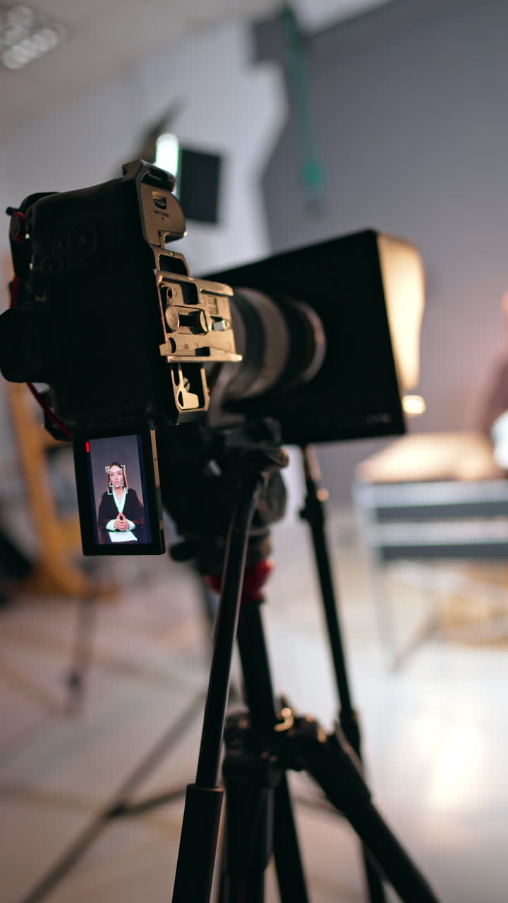 Caucasian lady talks and gestures on the camera display. Close up of a camera taking video in modern studio. Vertical video.