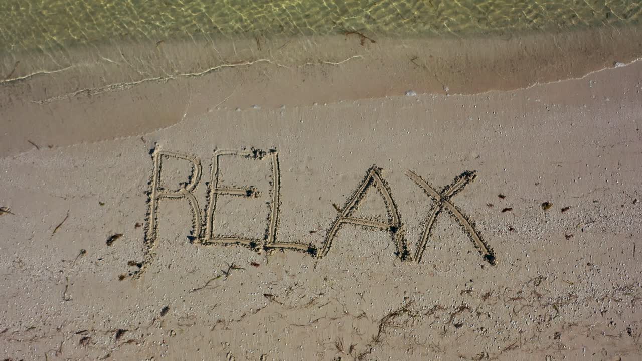 RELAX written in the sand and spinning clockwise