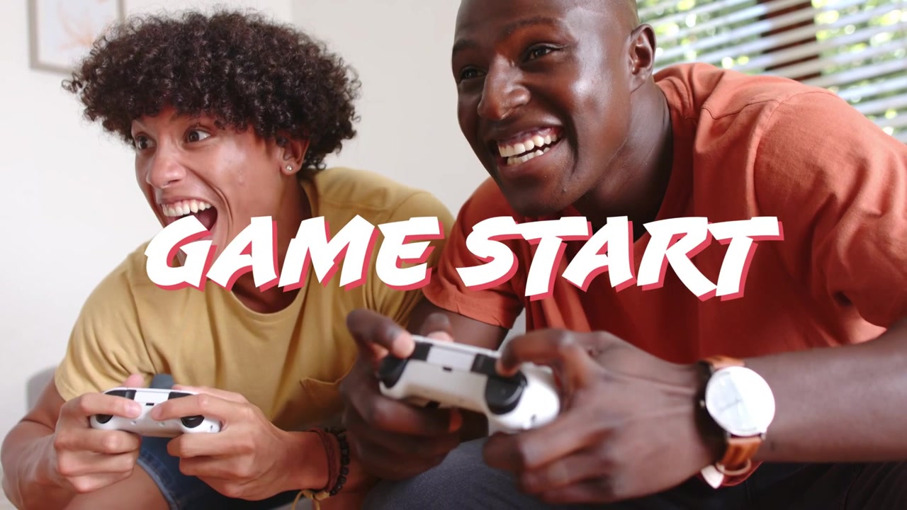 Due uomini seduti sul divano reagiscono a "GAME START", slanciandosi e afferrando controller bianchi per la partita.