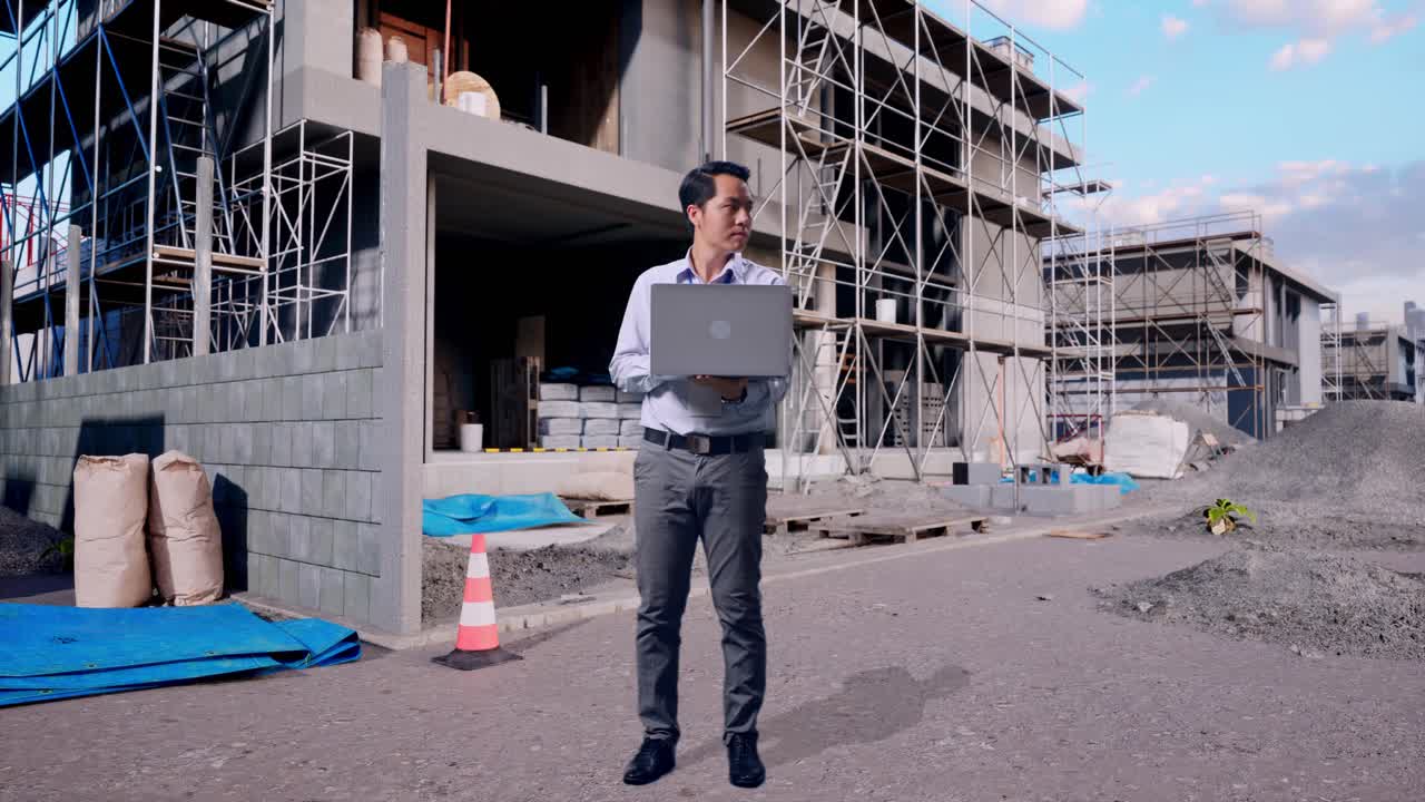 Full Body Of An Asian Male Professional Worker With His Laptop At Construction Site in Progress to New House, He Observes By Looking Around Before He Come To Concentrating With His Laptop
