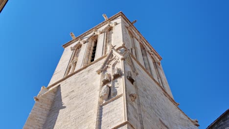 camera tilts upward along saint-sauveur church in la rochelle, showing stone walls and stained glass windows- france