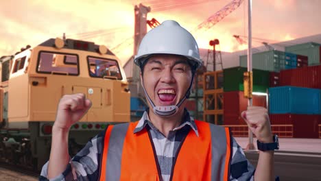 close up of asian male engineer with safety helmet screaming goal celebrating working with freight cargo train at port