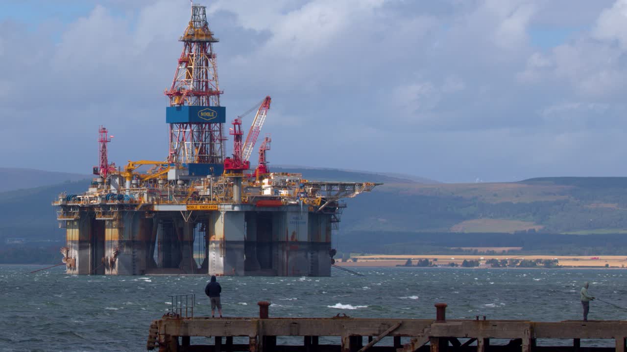 Olieboreplatform offshore, person på mole, dagslys, bredt billede, højlandslandskab, roligt kamera