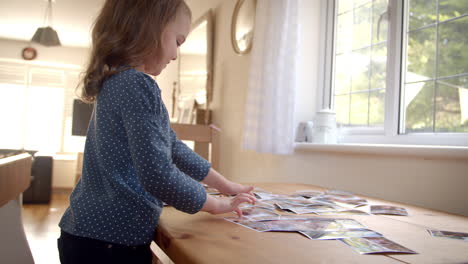 Junges-Mädchen-Schaut-Sich-Zu-Hause-Familienfotos-Auf-Dem-Tisch-An